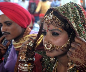 An Indian bride sits with her groom duri